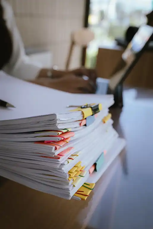 Organized stack of compliance documents with colored tabs on an office desk representing nonprofit documentation management