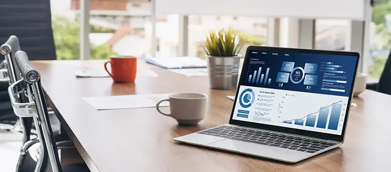 Laptop on office desk displaying a business dashboard with organized reports and data summaries